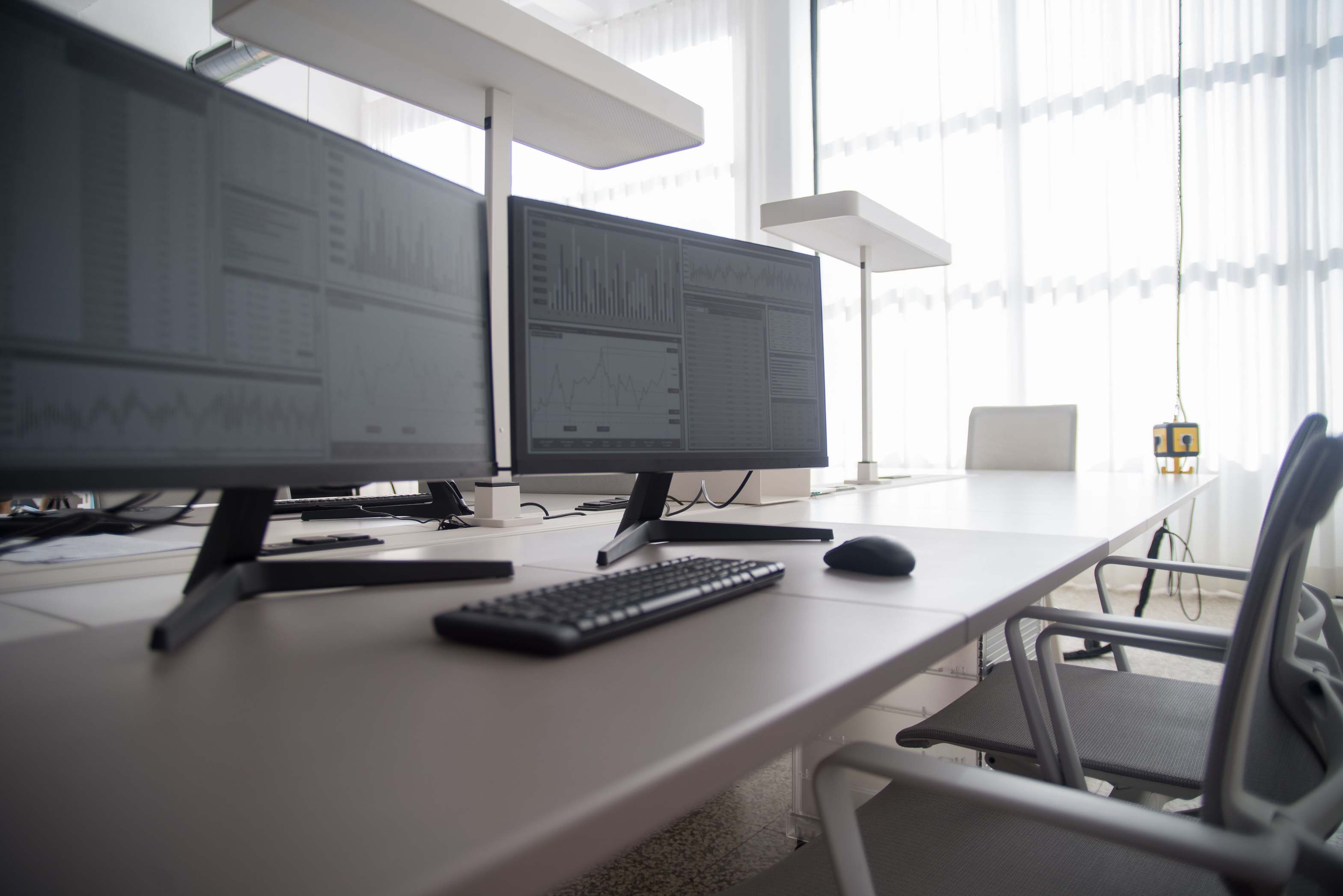 Desk with monitors showing development tooling, contemporary office with multiple computer monitors